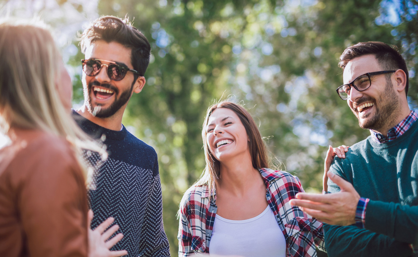 two men and two women laughing outside in the sun