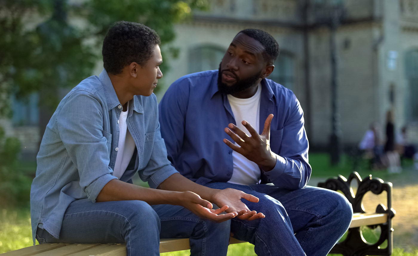 father talking to son on bench outside