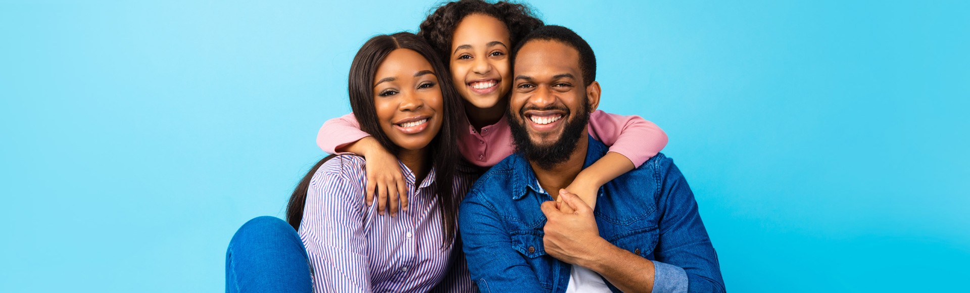 Black parents with their daughter sitting on the floor smiling