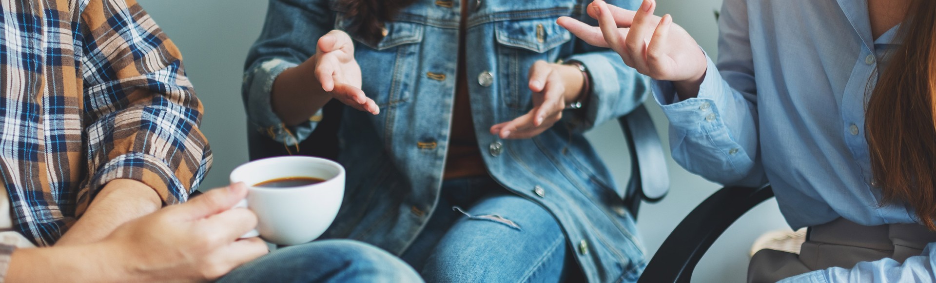 three people chatting sitting in chairs with coffee