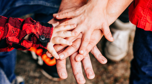 the hands of a family with a young child